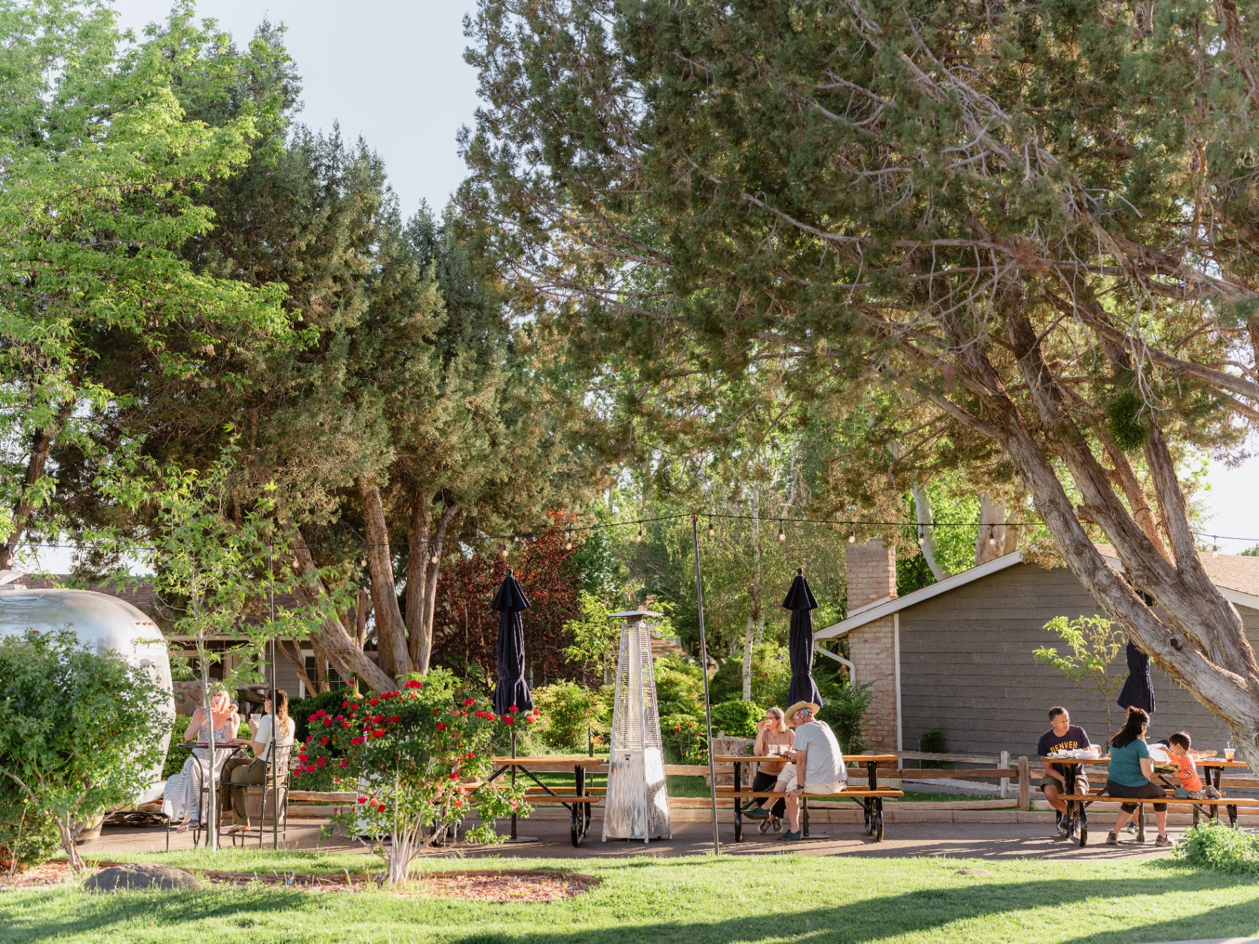 Outdoor garden seating with picnic tables and string lights for a group gathering